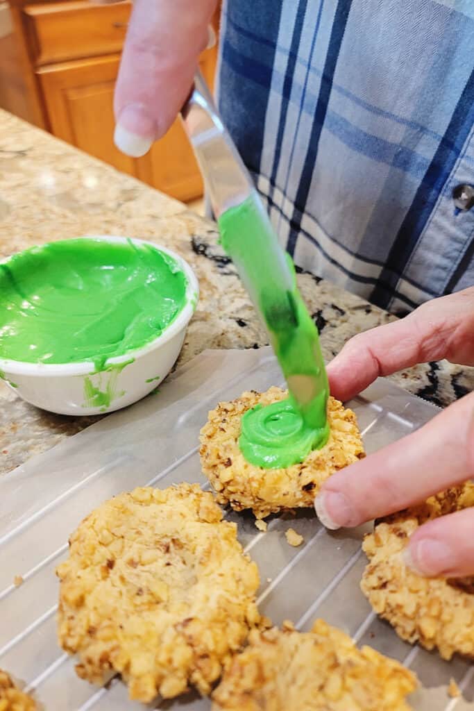 adding green frosting to thumbprint cookie