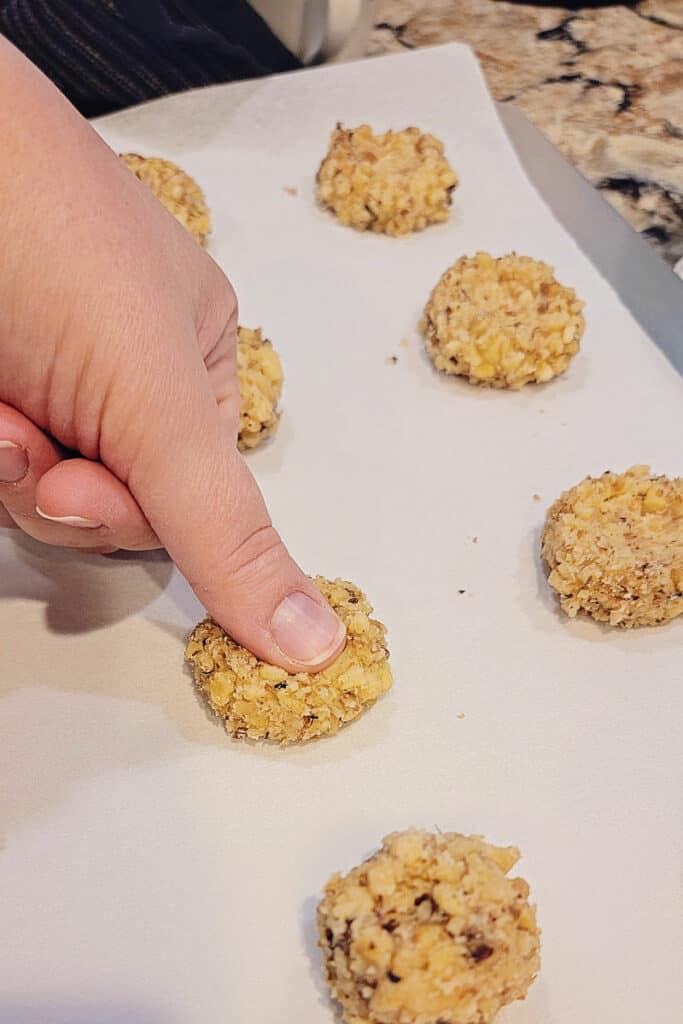 pressing thumb into walnut cookies
