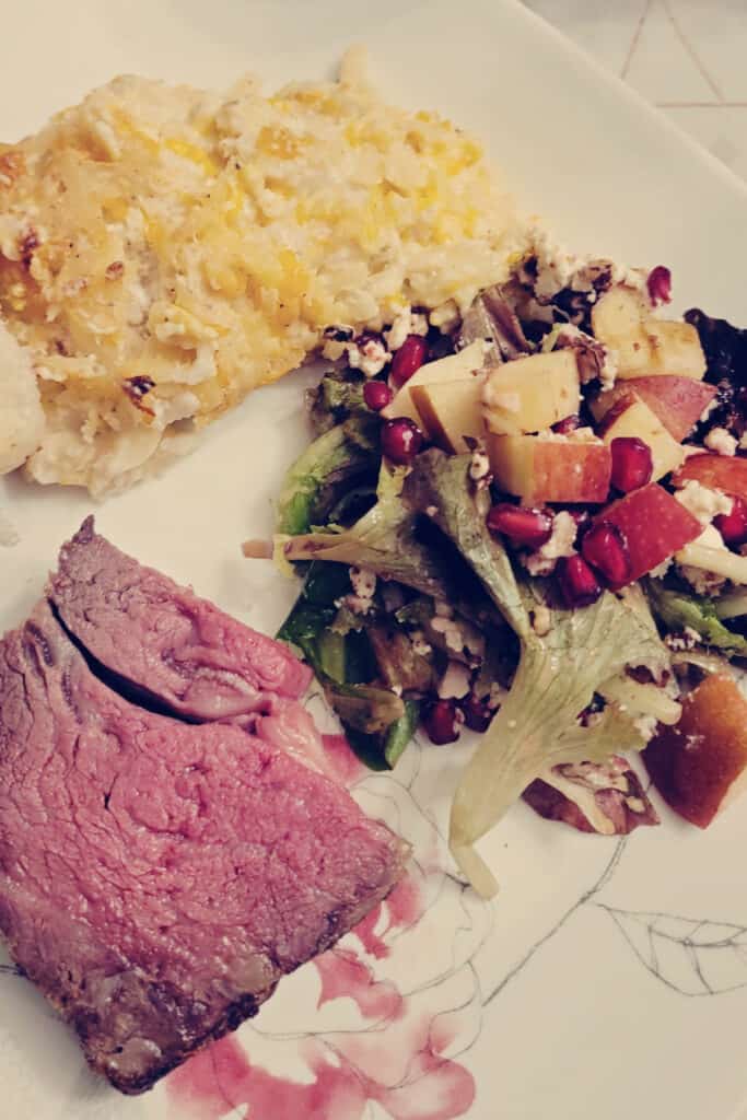 prime rib, cheesy potatoes and salad dinner on plate