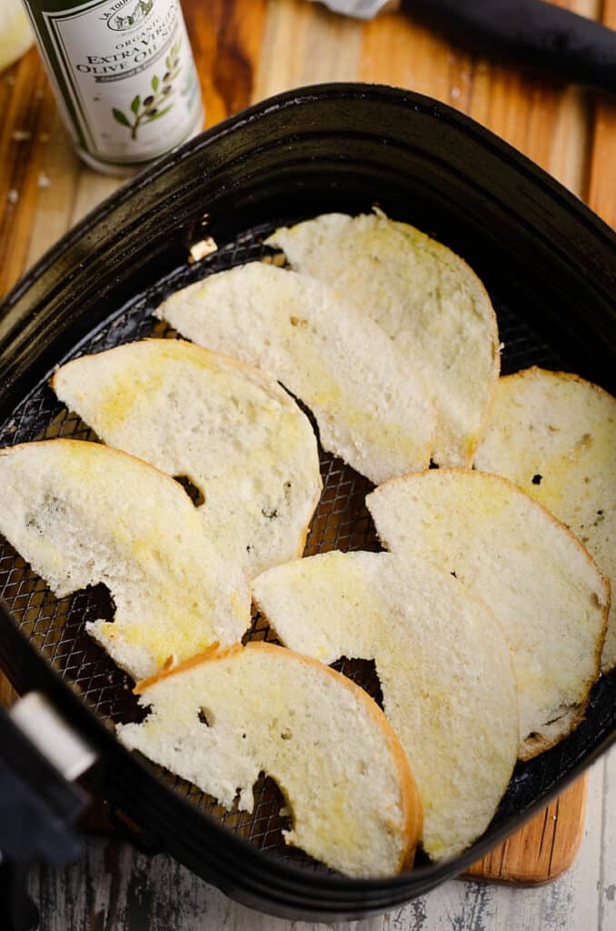 bagel chips in air fryer basket sprayed with oil