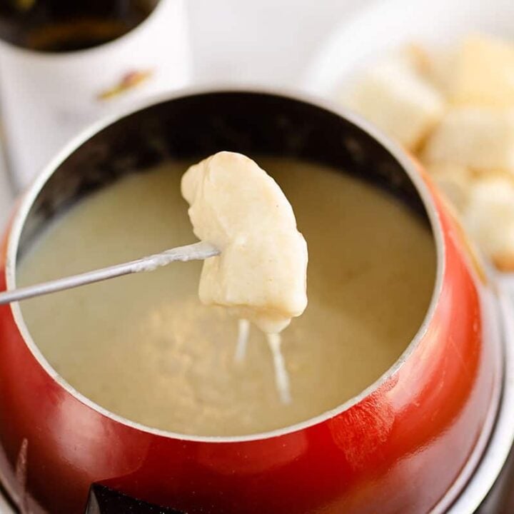 piece of bread dipped in fondue pot with cheese pull
