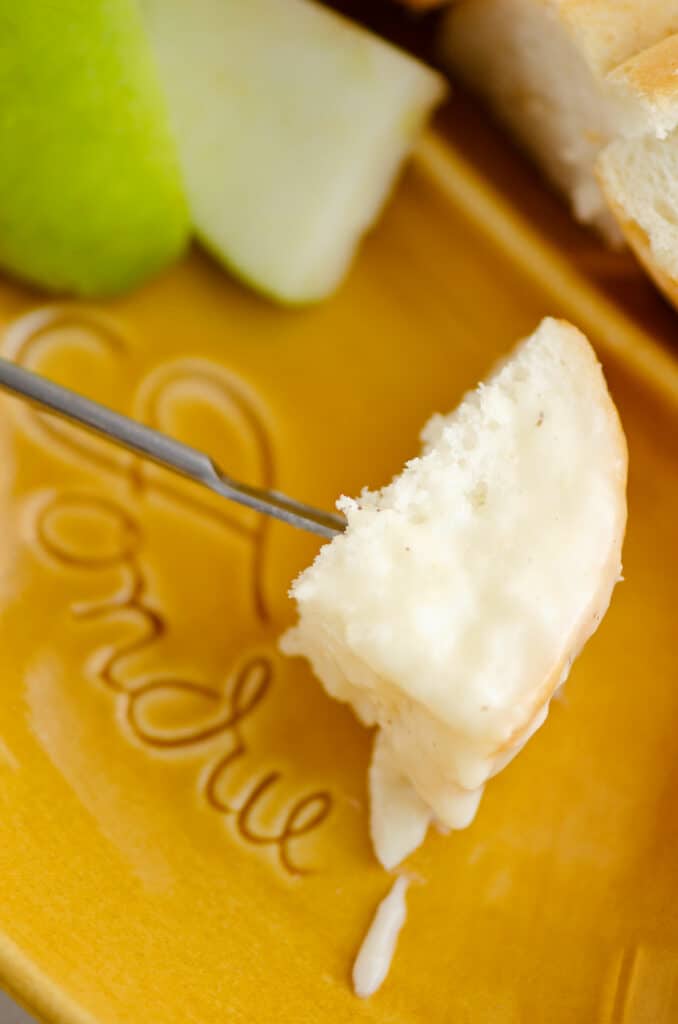 piece of bread on fondue fork with Swiss cheese