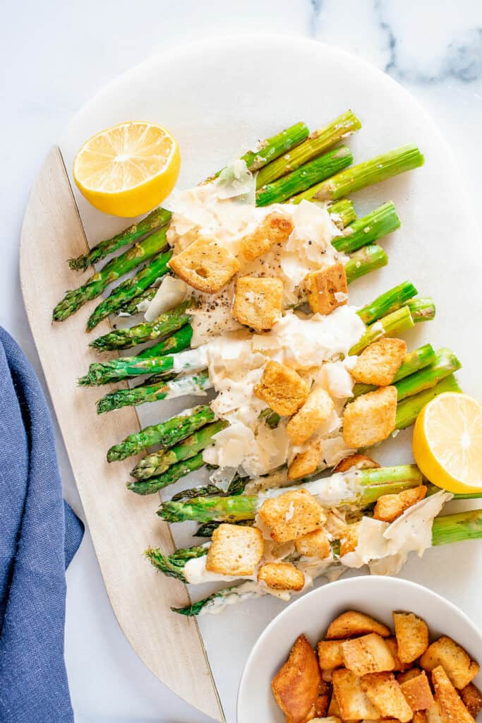 roasted Caesar asparagus on white serving platter with lemon halves