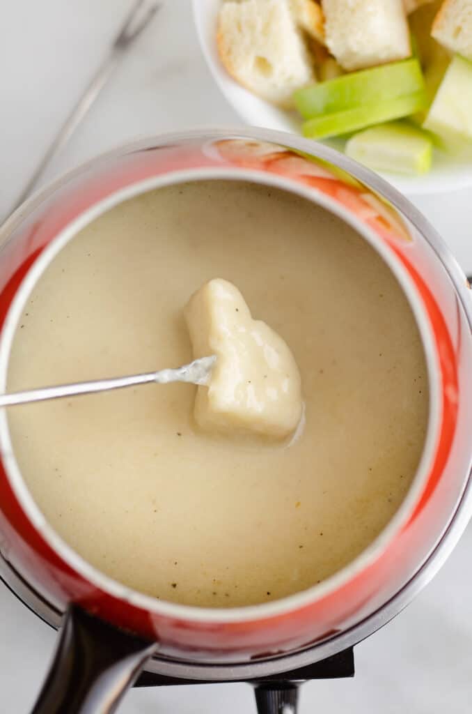 bread dipped in cheese fondue pot with fondue fork