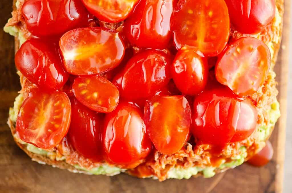 Buffalo Tuna Avocado Toast topped with cherry tomatoes and hot sauce