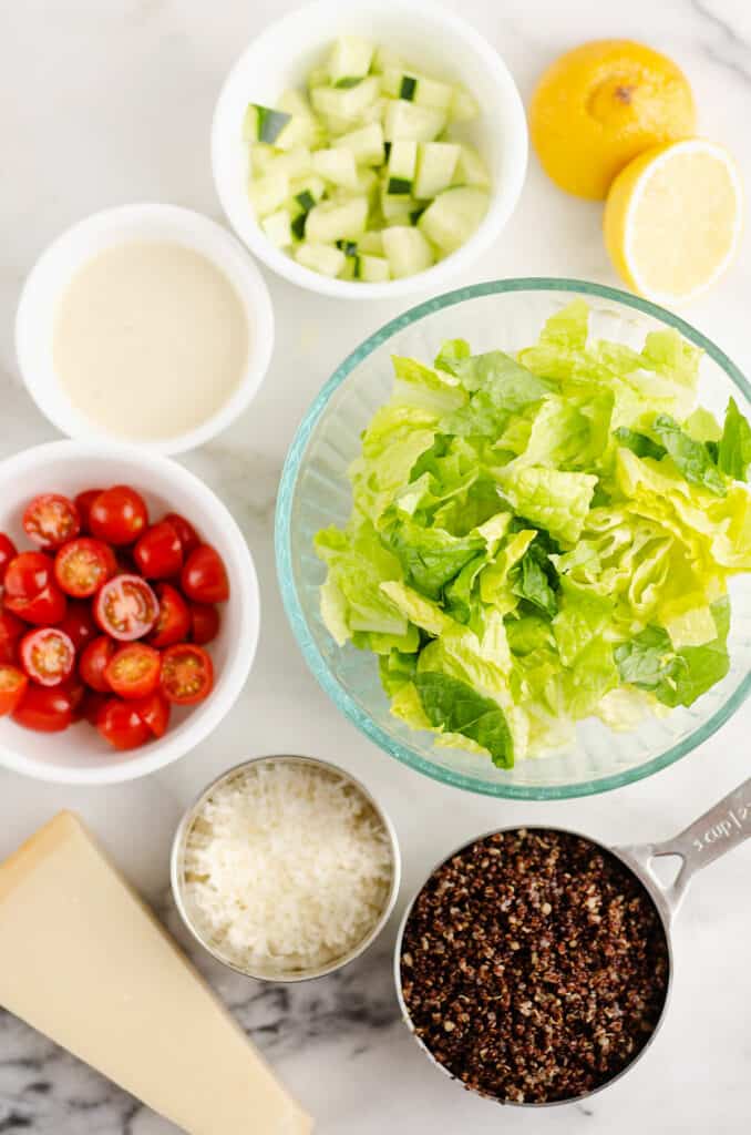 chopped caesar salad ingredients on white marble table