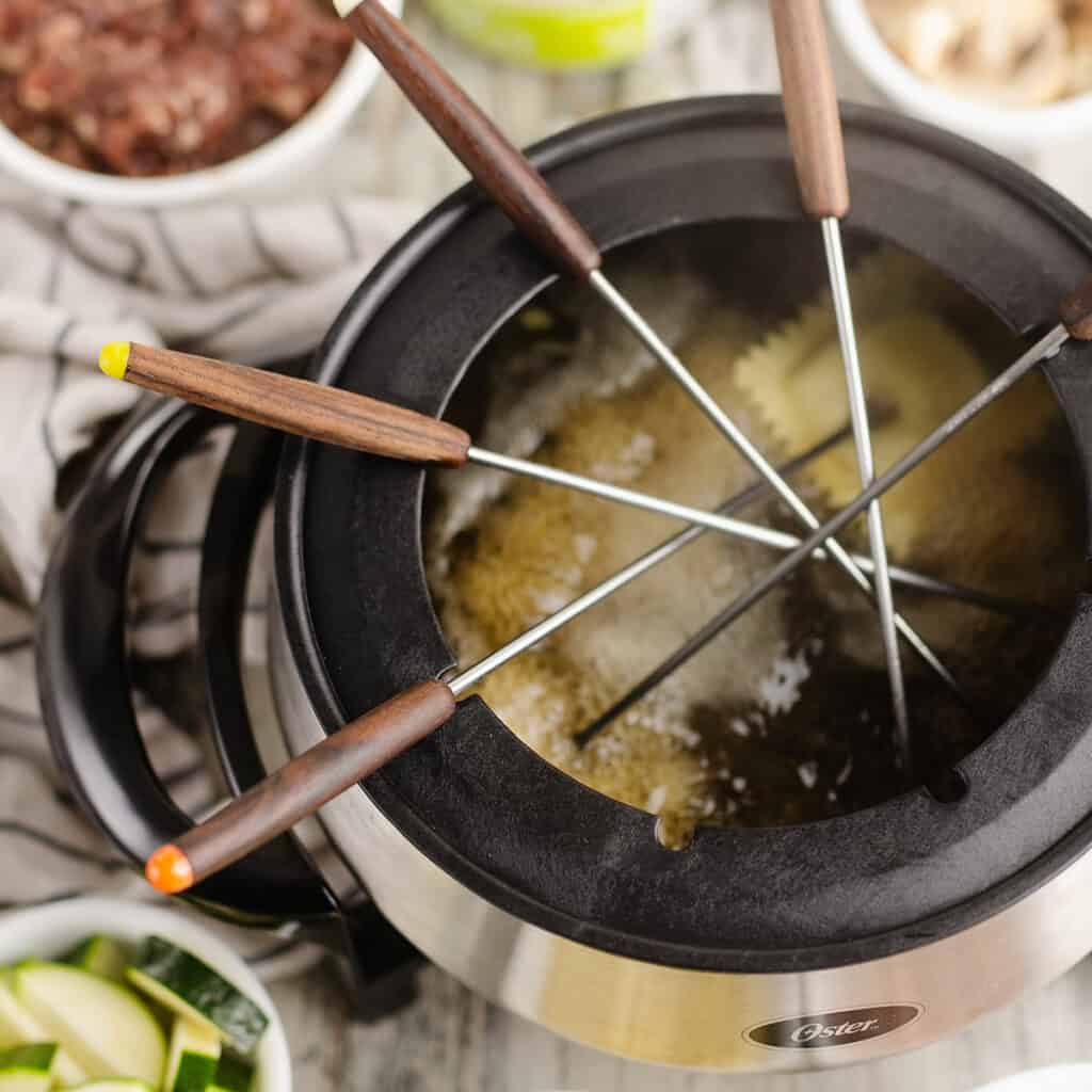 fondue pot filled with broth and forks