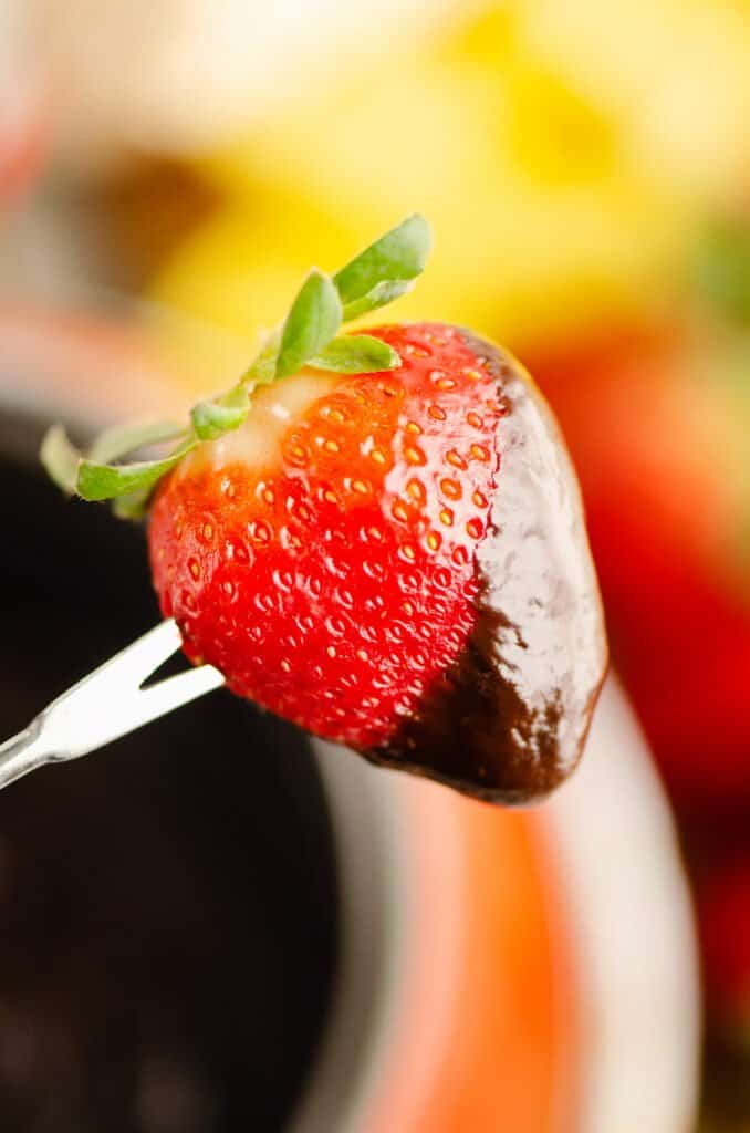 strawberry on fondue fork dipped in dark chocolate fondue