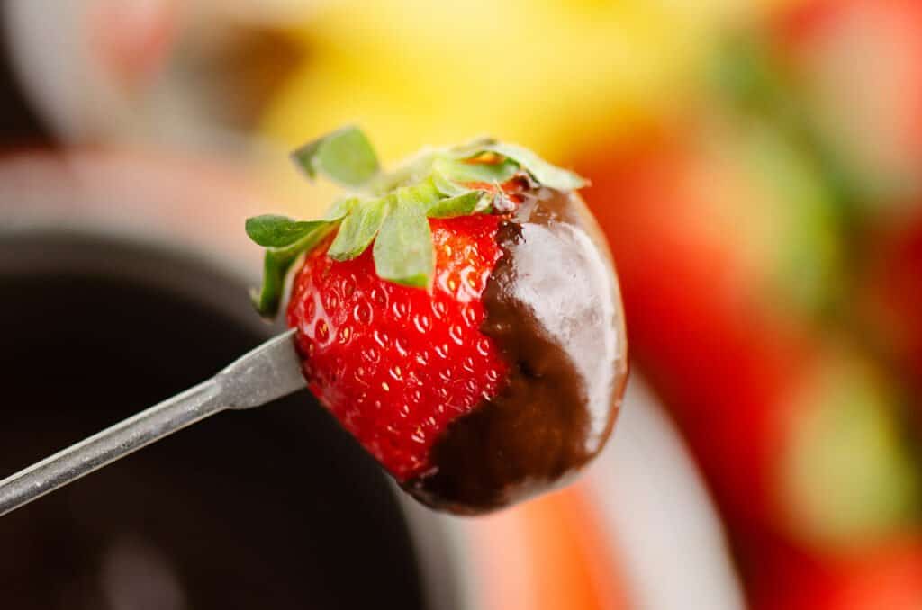 strawberry on fork dipped in dark chocolate fondue