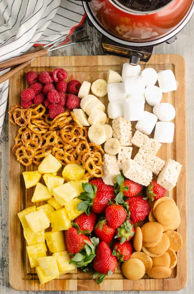 cutting board topped with chocolate fondue dippers and fondue pot