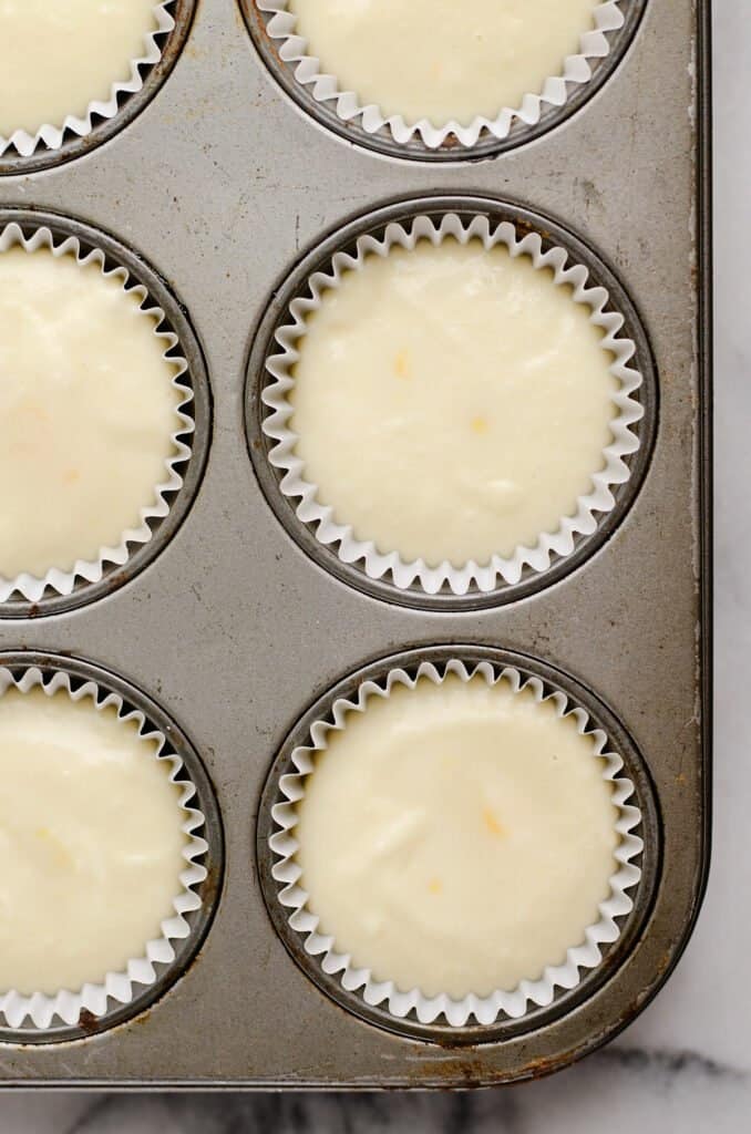 orange cupcake batter in lined muffin tin