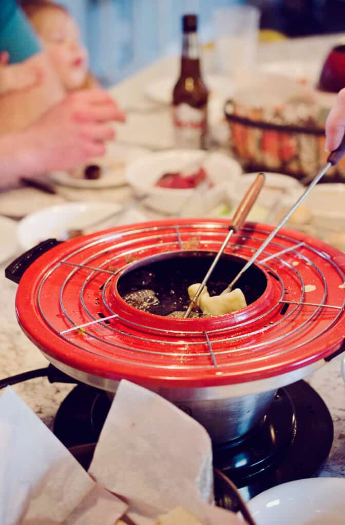 vintage fondue pot filled with hot oil and cooked food on forks