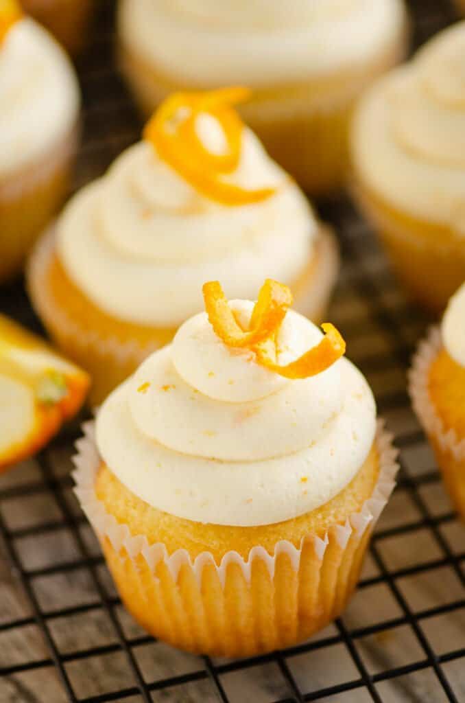 orange cupcake topped with buttercream on cooling rack