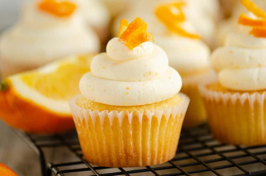 orange cupcakes on cooling rack with orange wedge