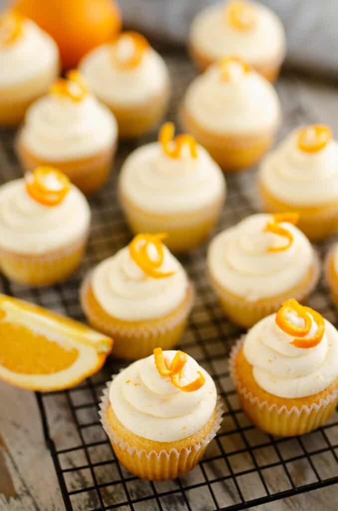 range cupcakes on cooling rack with orange wedge