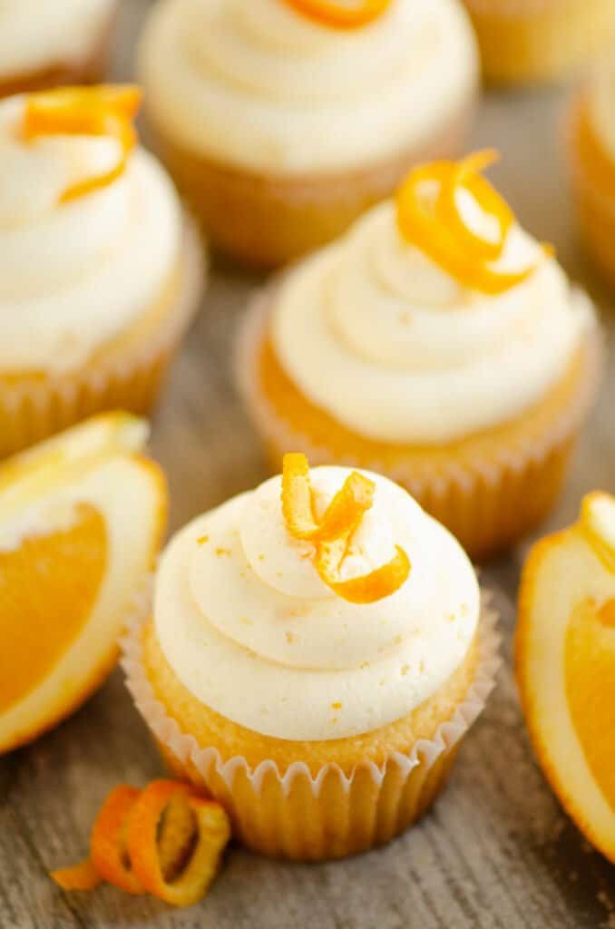 orange cupcakes on table with orange wedges and peels