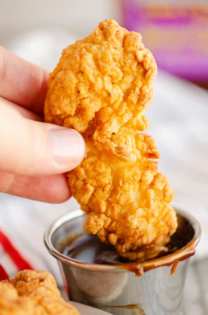 chicken strip being dunked in BBQ sauce