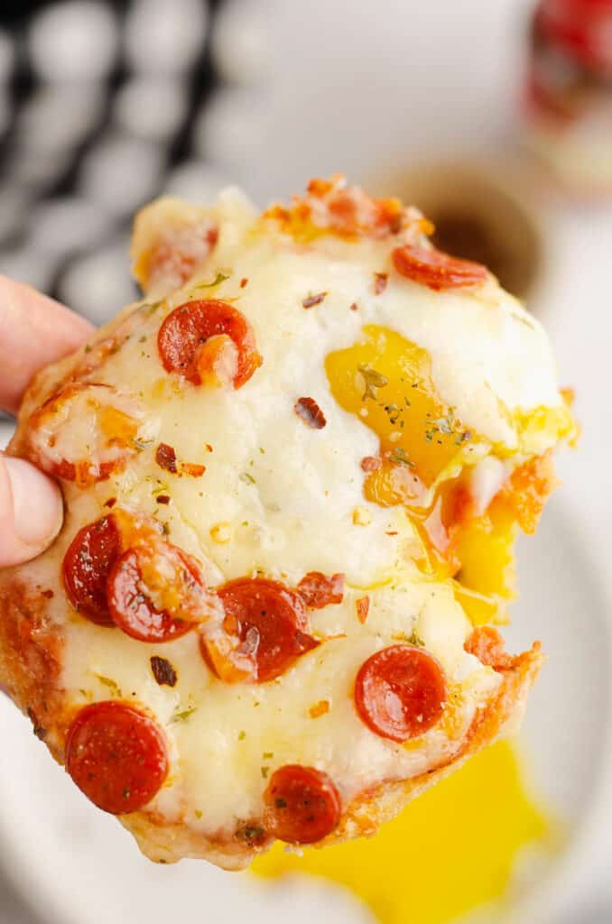 english muffin breakfast pizza held in hand