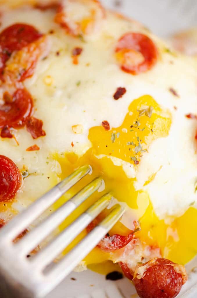 runny egg yolk on english muffin pizza with fork in it