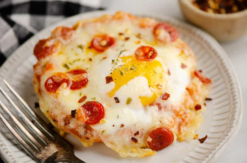 english muffin egg pizza on plate with fork on table