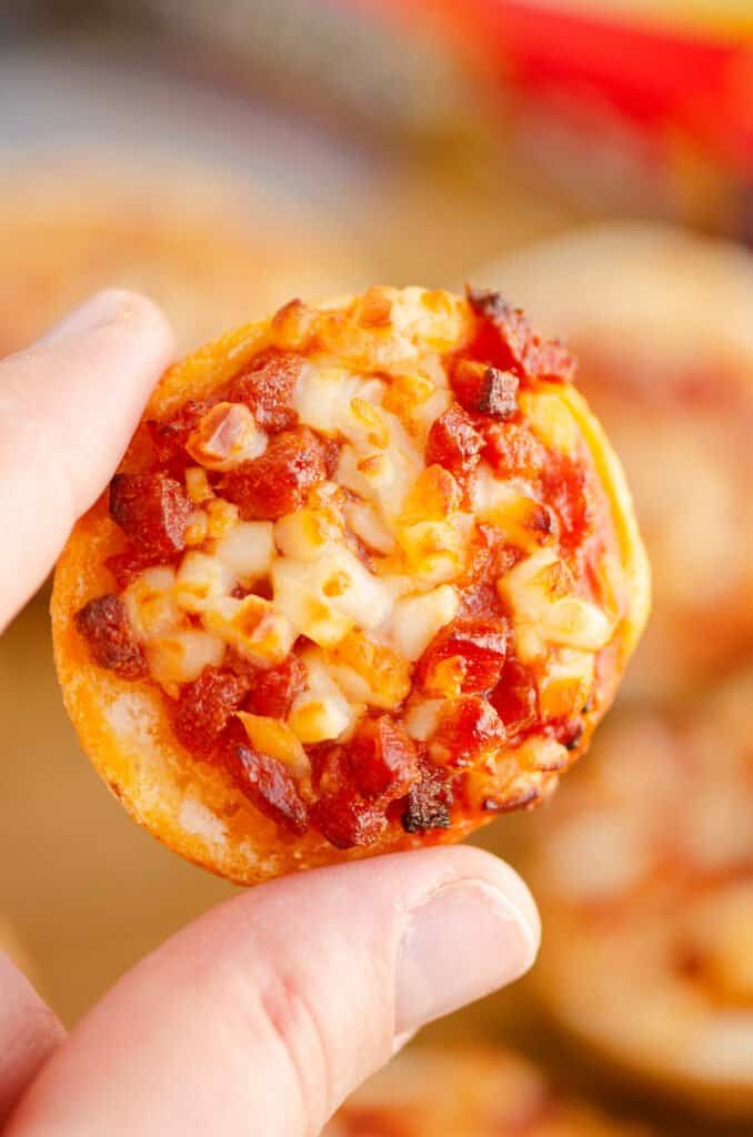 fingers holding pepperoni bagel bite