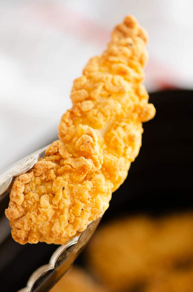 crispy chicken strips in tongs