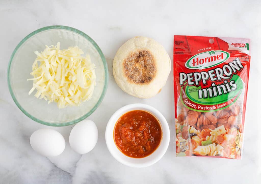 cheese, eggs, english muffin, pizza sauce and pepperoni on marble table