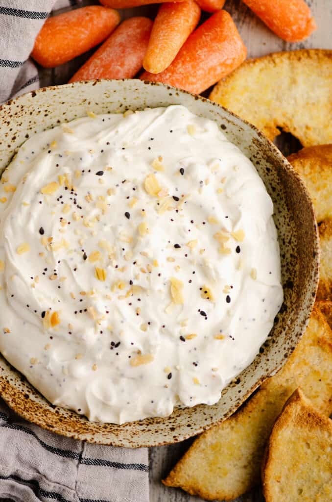 homemade bowl filled with everything bagel dip served with carrots and bagel chips