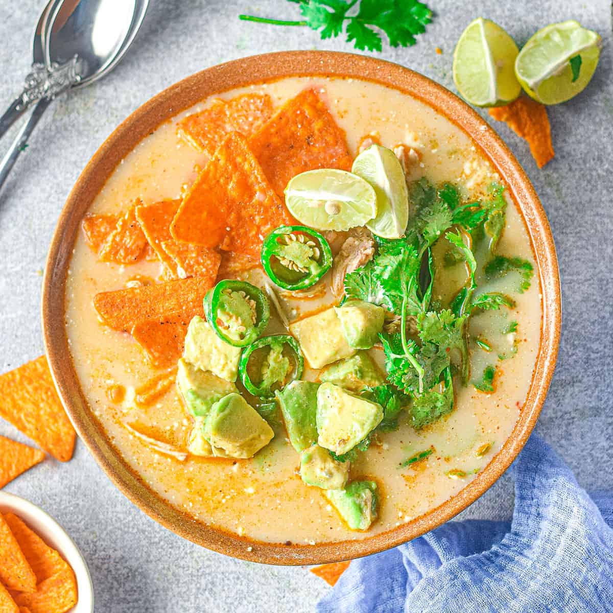 bowl of chicken jalapeno corn soup on table with chips and napkin