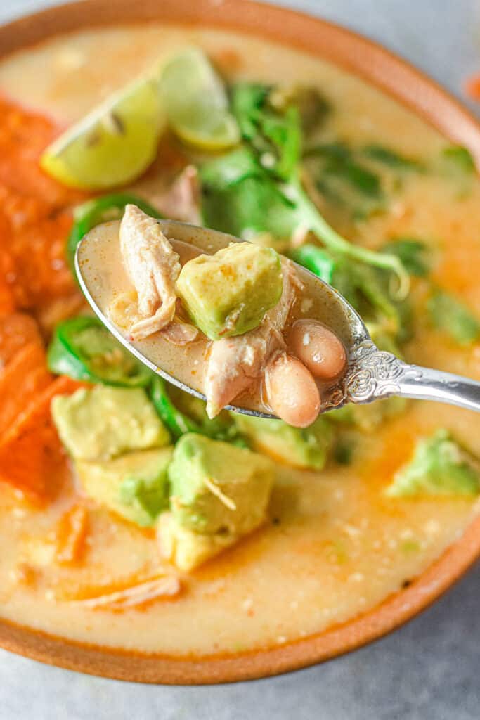 bowl of chicken jalapeno corn soup with spoonful garnished with avocado