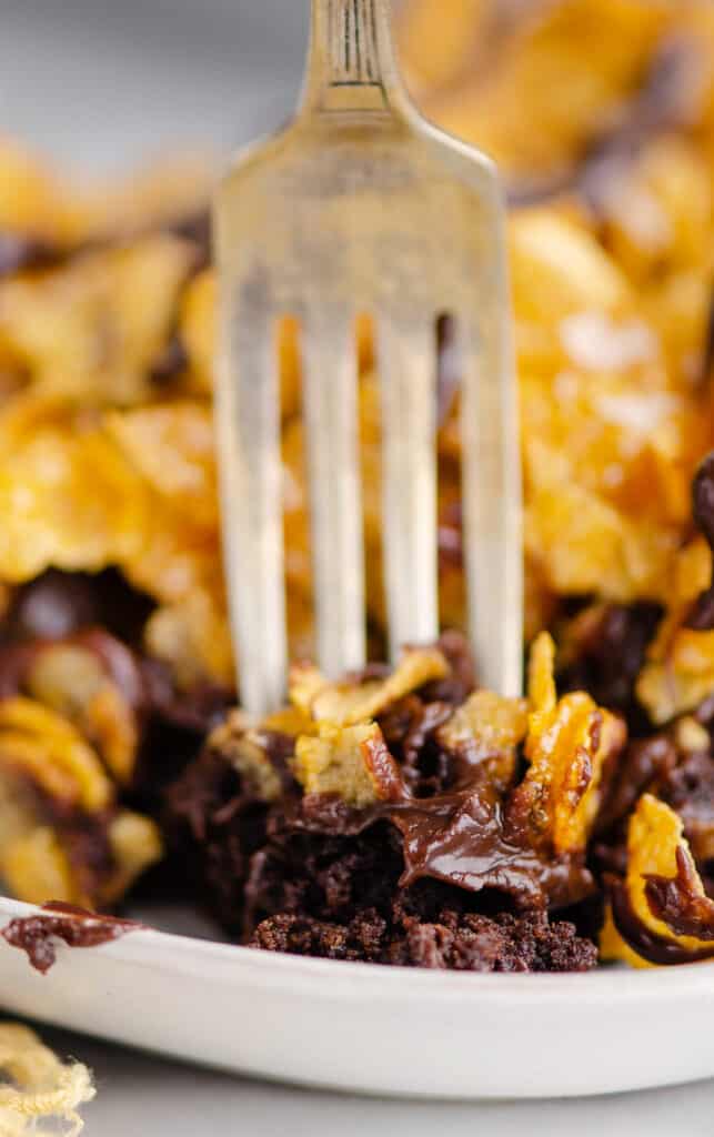 fork taking bite out of layered brownies on plate