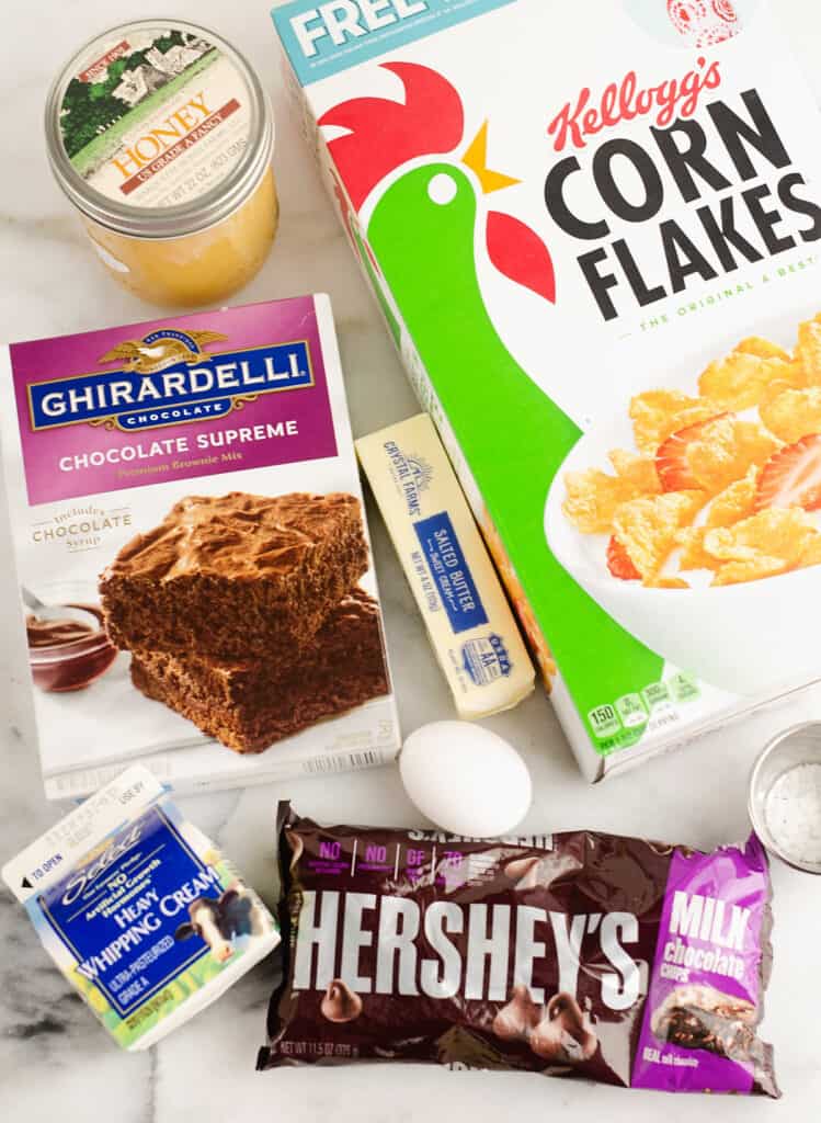 cornflake box, honey jar, brownie mix, cream, egg and chocolate chips on marble kitchen counter