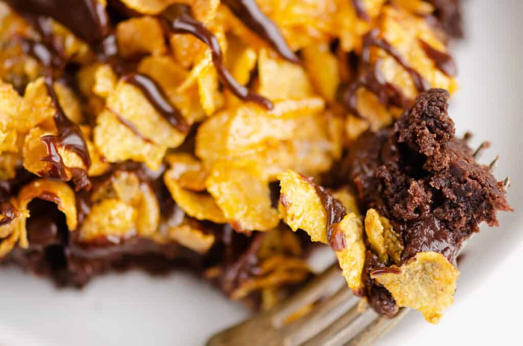 ghirardelli brownies with ganache and cornflakes on plate with bite on fork
