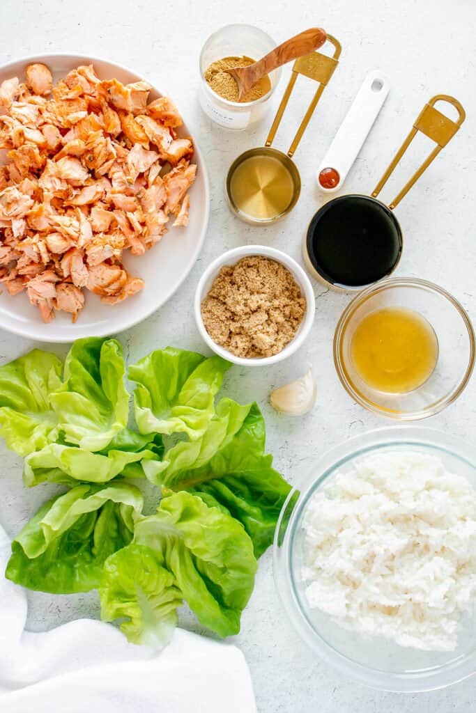 salmon, lettuce, rice and teriyaki ingredients on white table