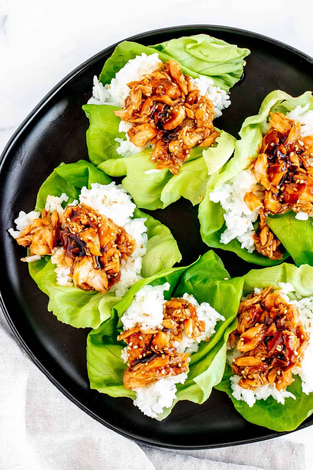 leftover salmon, teriyaki and rice lettuce cup on plate with white napkin