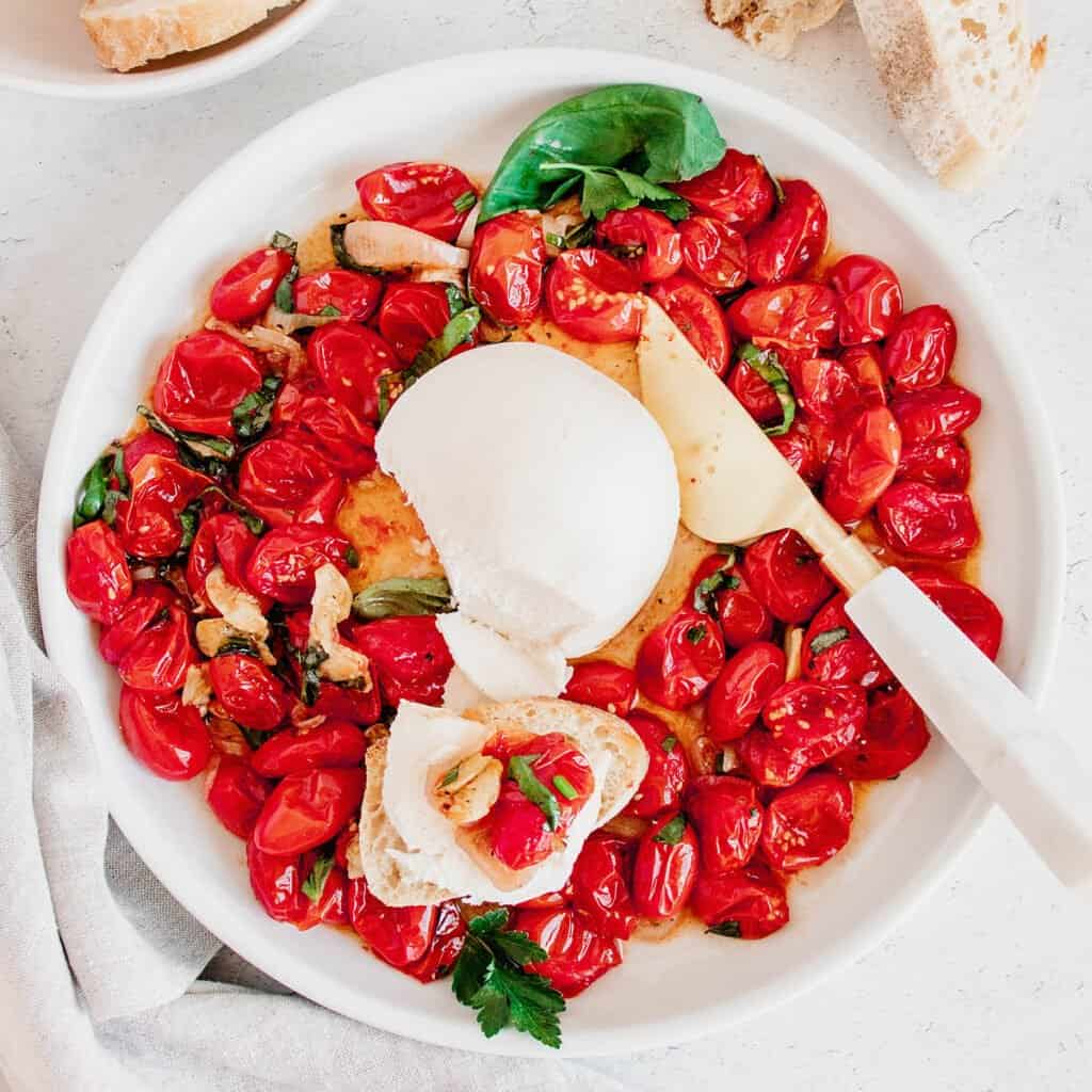 roasted tomatoes and mozzarella ball on platter with cheese knife