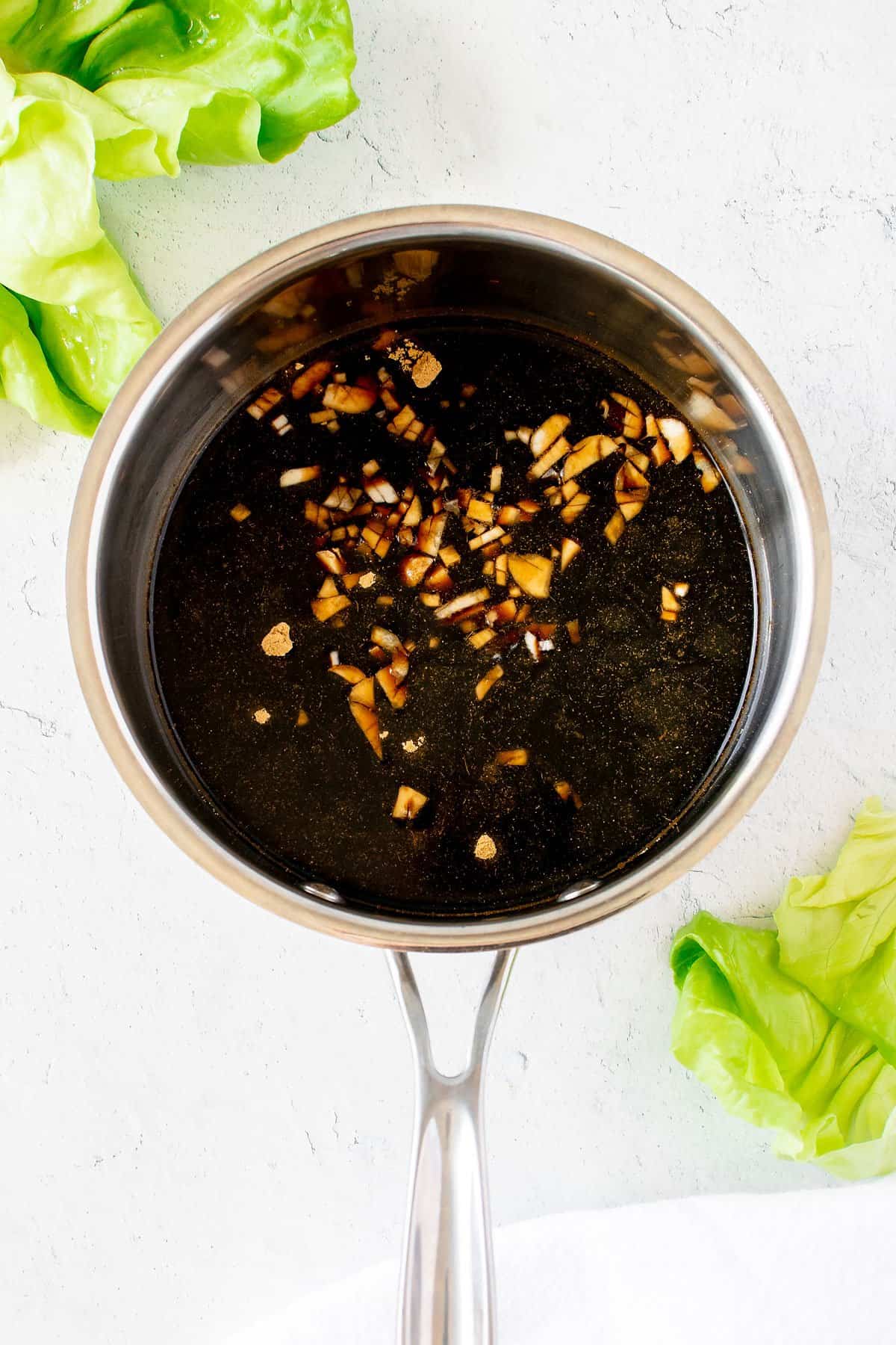 homemade teriyaki sauce in saucepan on table with butter lettuce