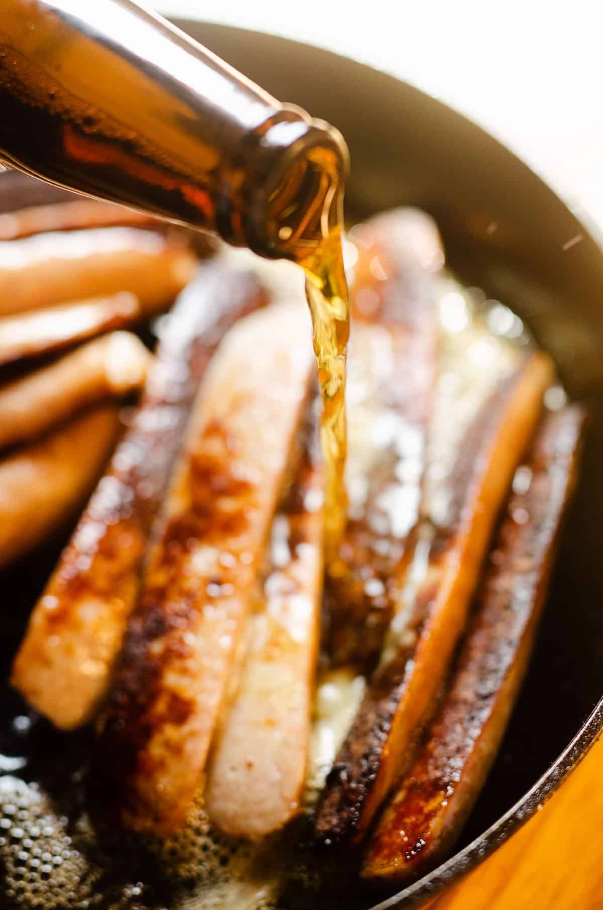 beer poured over brats in pan
