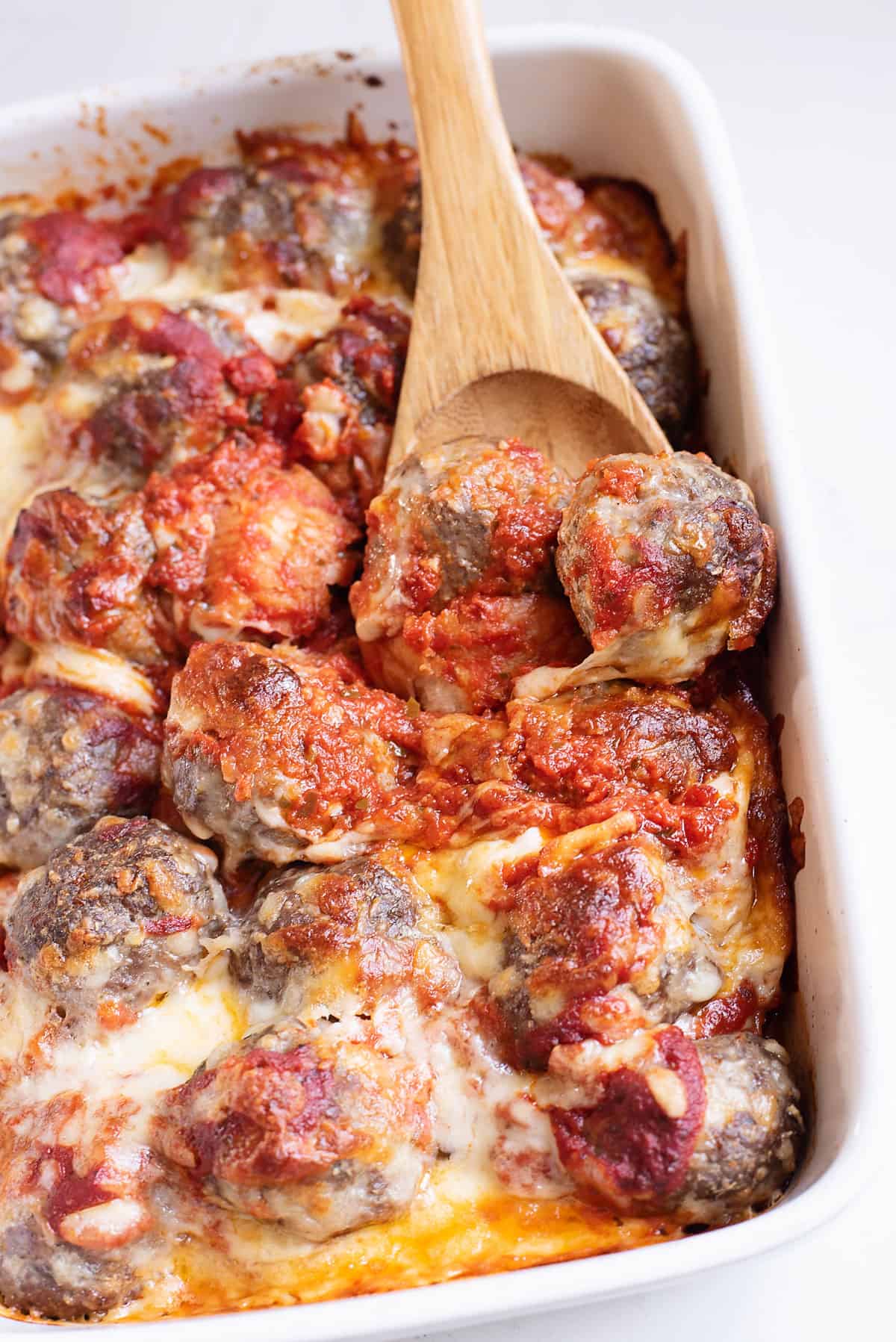 cheesy meatball sub casserole in baking dish with wooden spoon