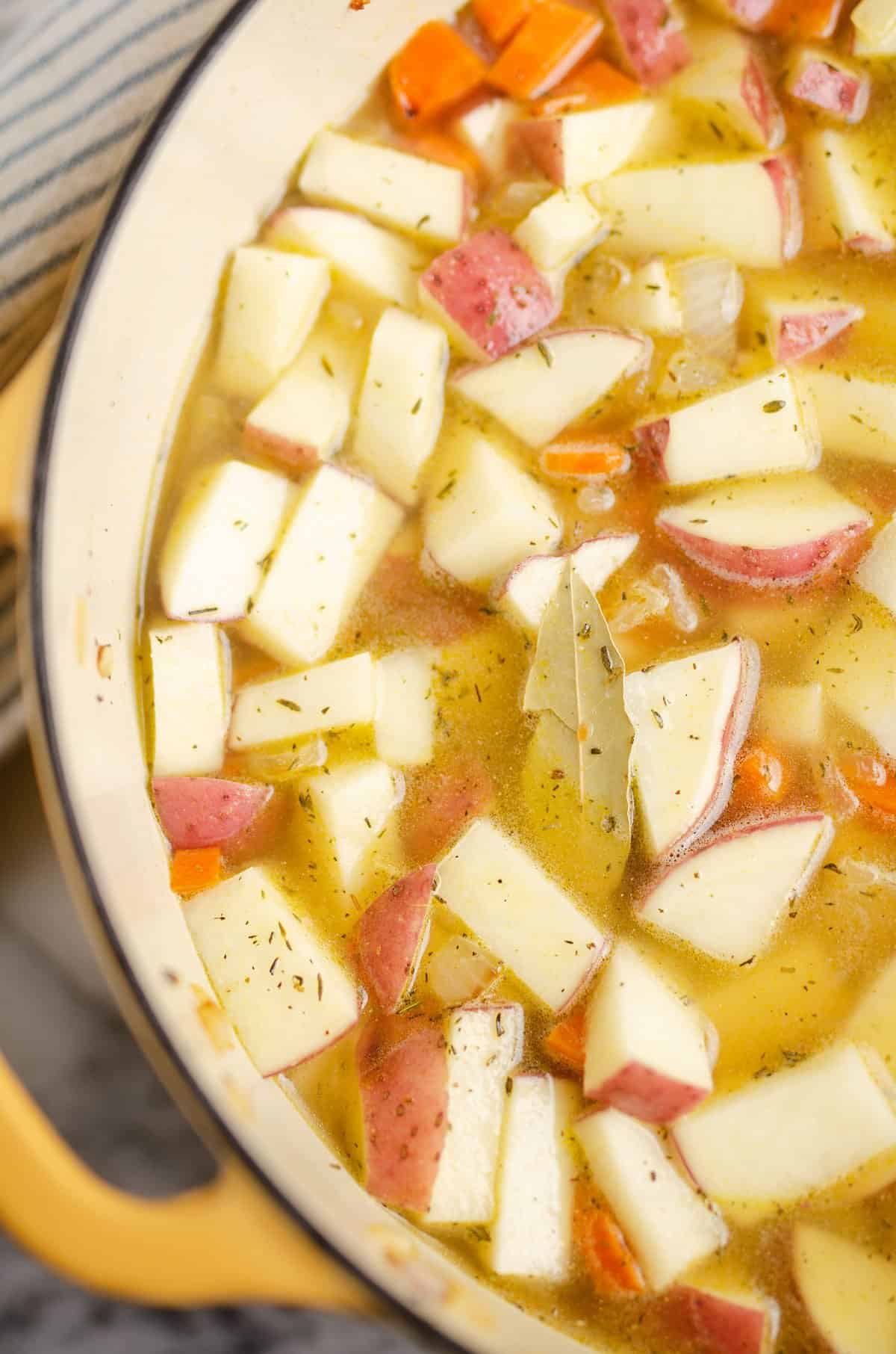 red potatoes, carrots and bay leaf in soup pot