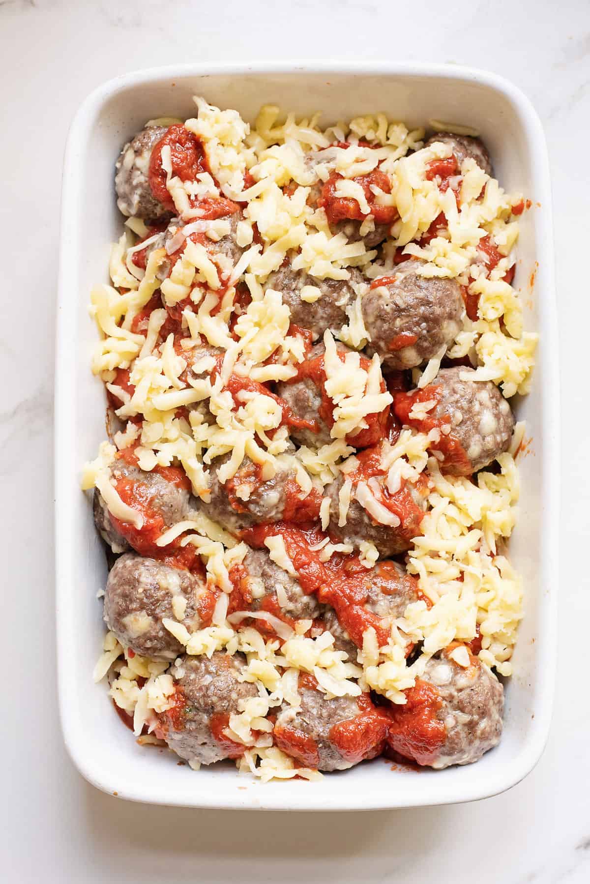 meatballs and marinara in baking dish topped with cheese