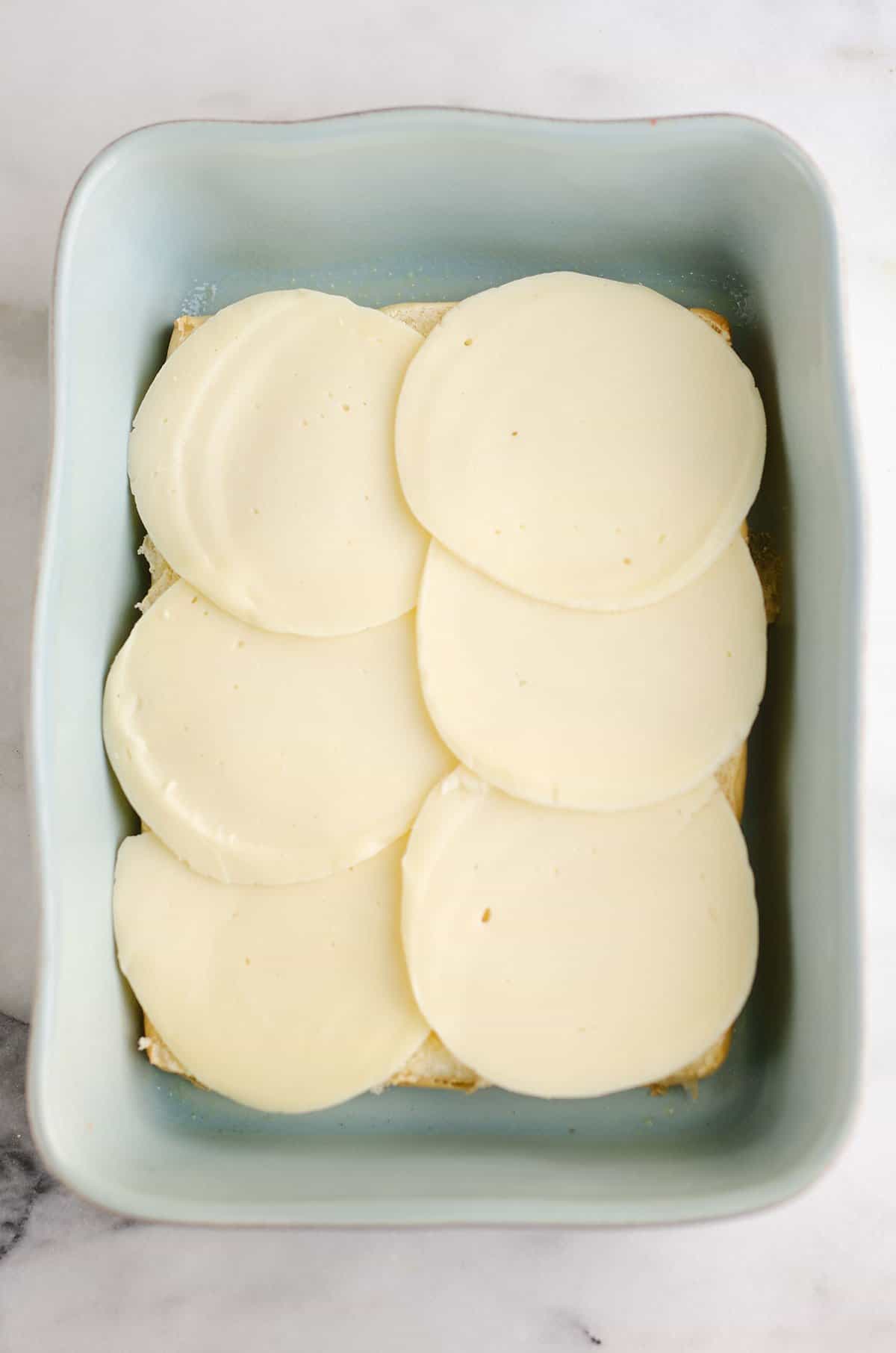 provolone cheese over buns in blue pan