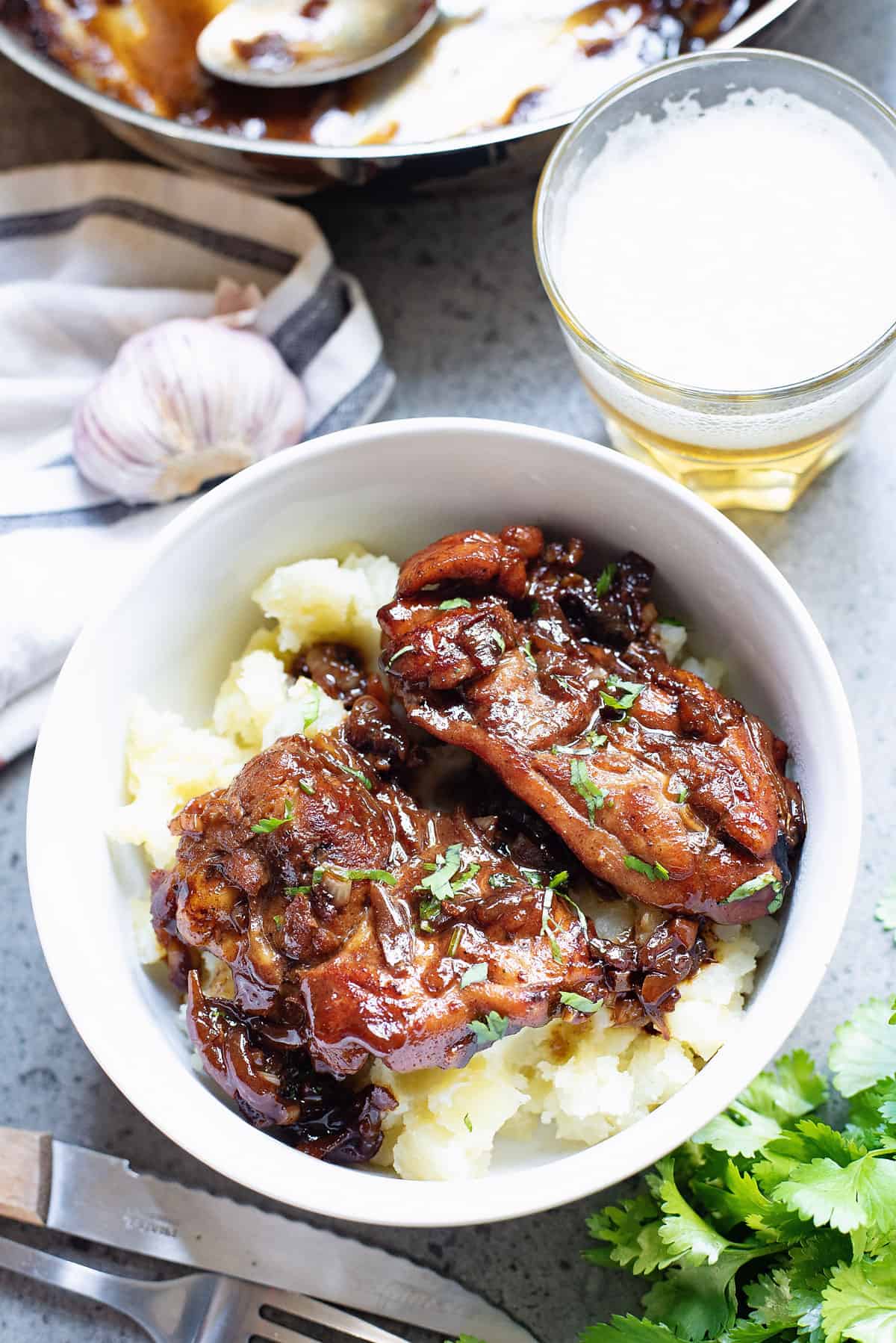 honey chicken thighs in white bowl with potatoes and glass of beer