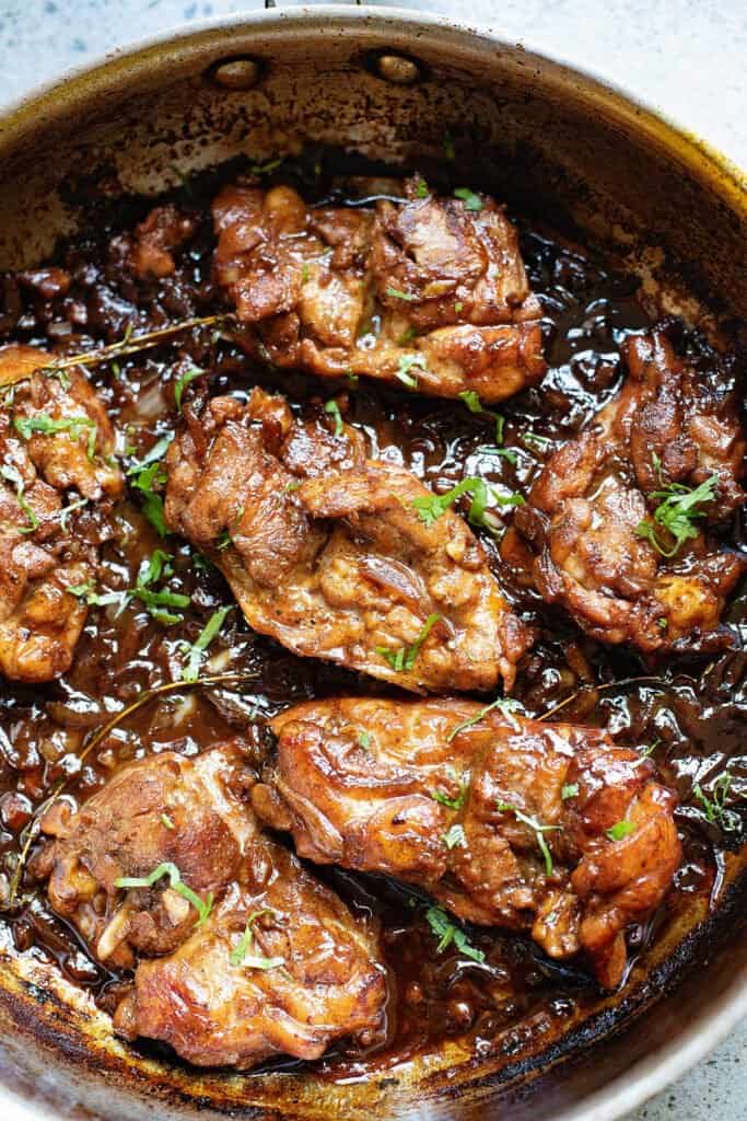 honey beer chicken thighs in pan with onion gravy and cilantro