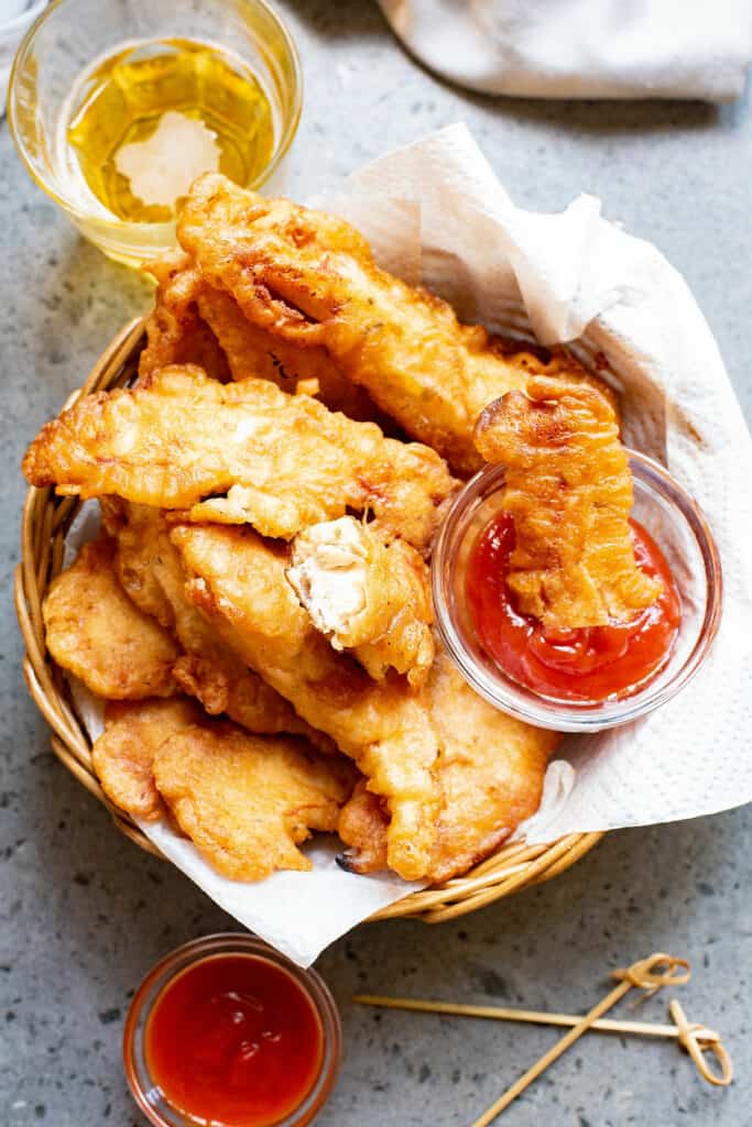 beer battered chicken tenders in lined basket and dunked in ketchup