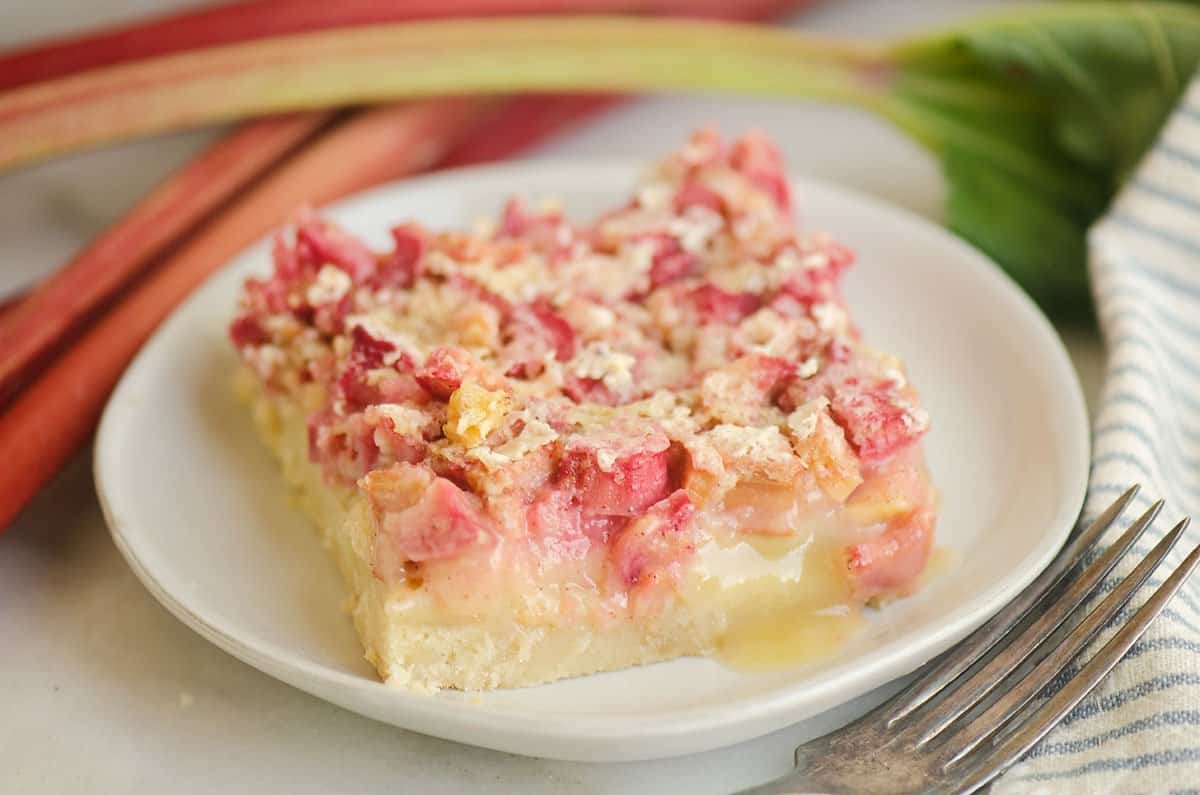 rhubarb dream bar on plate with fork and rhubarb stalks