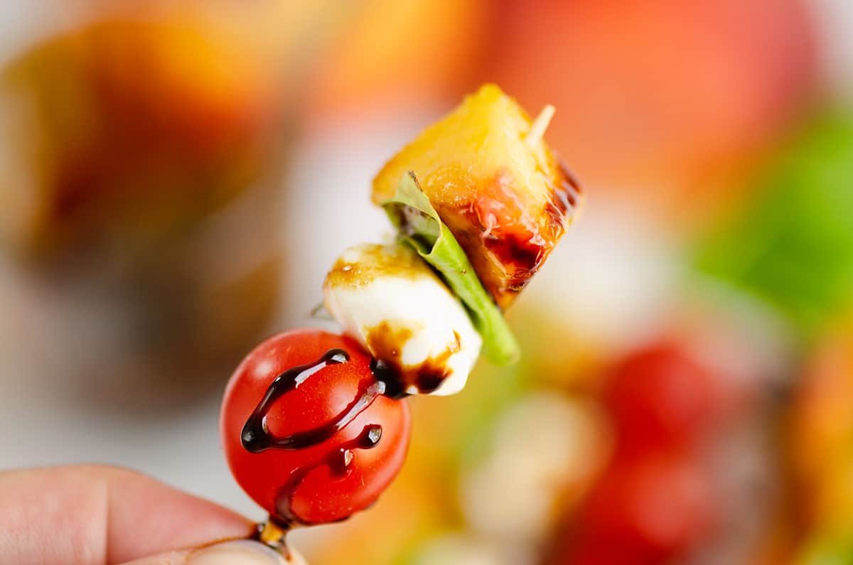 peach, basil, mozzarella and tomato on toothpick with balsamic glaze drizzle