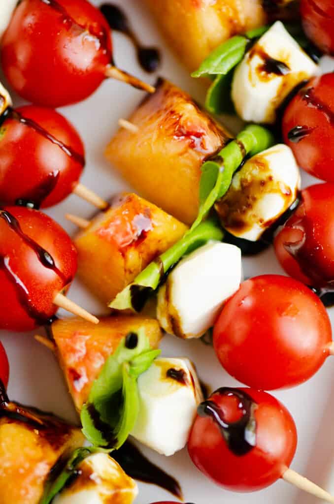 peach and tomato skewers on platter with balsamic drizzle