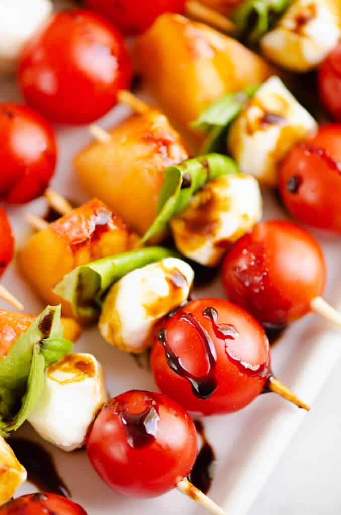 caprese toothpick skewers drizzled with balsamic glaze on platter