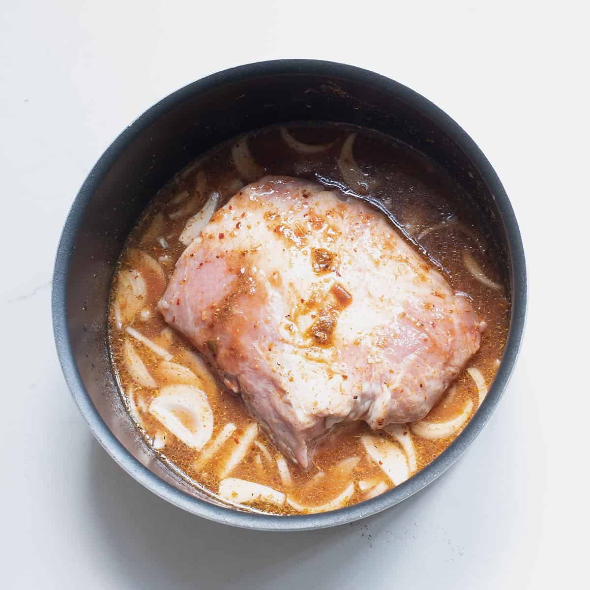 pork butt in pot with broth and onions